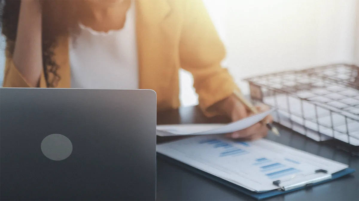 Personne consultant des documents et graphiques, symbolisant un diagnostic.